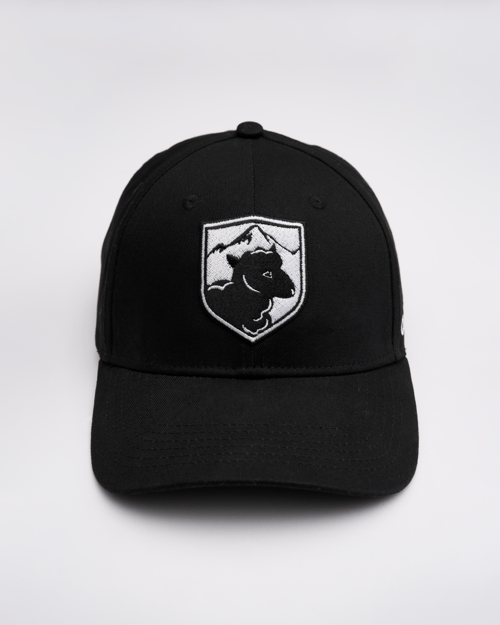Black cap with a white logo featuring a sheep and mountains