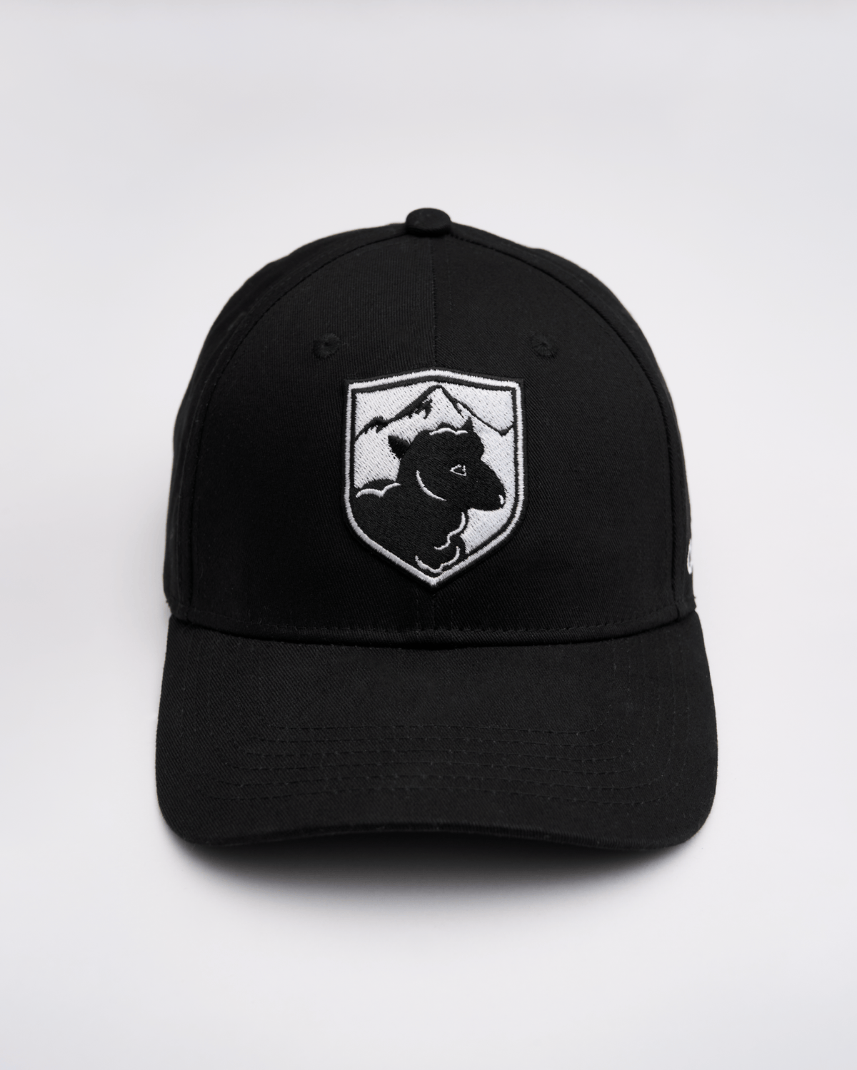 Black cap with a white logo featuring a sheep and mountains